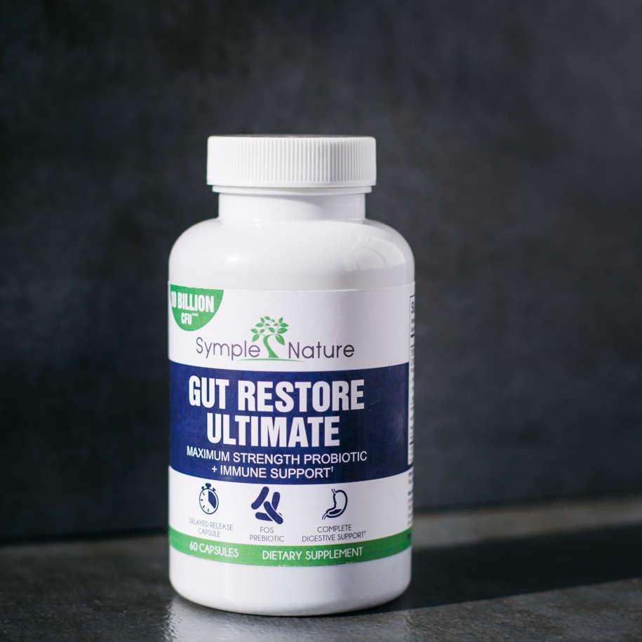 Gut Restore Ultimate bottle on dark counter with capsules spilled beside it